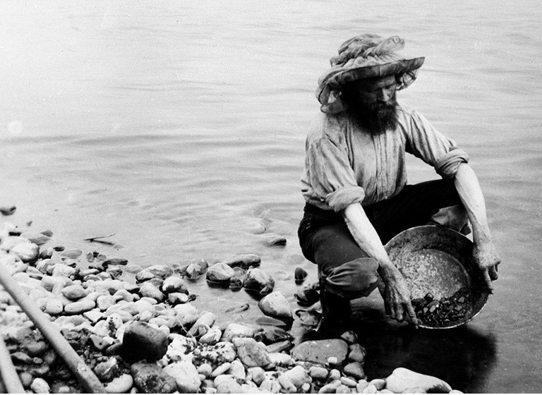 A prospector pans for gold in Yukon circa 1897.